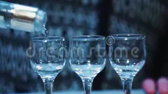 一个酒吧酒保用三个杯子的特写镜头从瓶子里倒伏特加视频的预览图