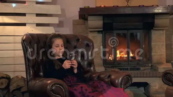 晚上穿着漂亮裙子的小女孩在家里用智能手机和朋友聊天视频的预览图