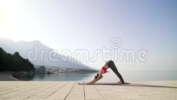 以山为背景在海边木板路上练习瑜伽体式的女人视频的预览图