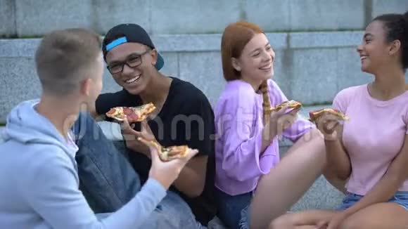 快乐的青少年在户外开玩笑吃披萨视频的预览图