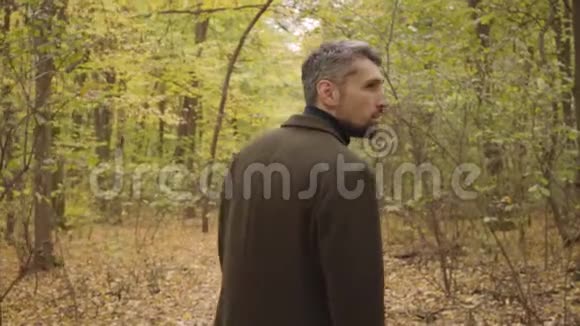一个白人成年人站在森林里四处张望穿着休闲服装的男人享受着宁静视频的预览图