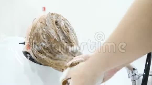 美容工作室用洗发水化妆和美容院洗头把发型师洗头发的手收起来视频的预览图