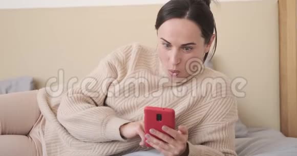 在床上使用手机的惊喜女人视频的预览图