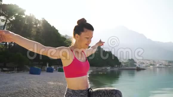 有发髻的成年妇女早上在海边练习瑜伽视频的预览图