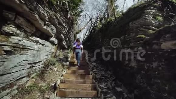 一个女孩爬上山裂谷中的石阶探索岩石的形成视频的预览图