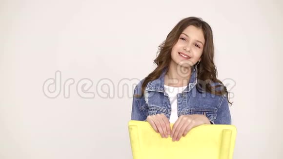一个小女孩坐在椅子上为摄影棚里的摄影师摆姿势视频的预览图