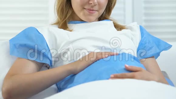 很高兴孕妇抚摸腹部躺在病床上产前护理育儿视频的预览图