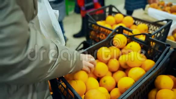超市里的女人选择橘子商店里的一盒橘子视频的预览图