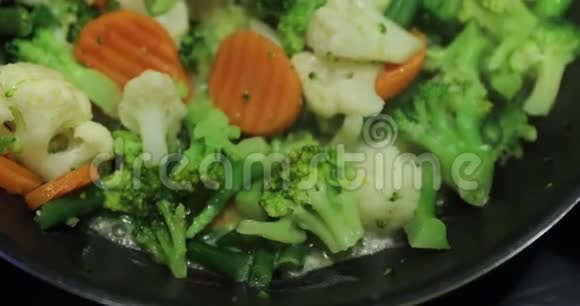 烹饪一种新鲜的切菜在煎锅上煎胡萝卜花椰菜西兰花哈里克打开盖子视频的预览图