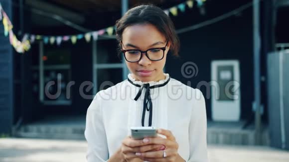 美国黑人青少年在户外使用智能手机微笑的肖像视频的预览图