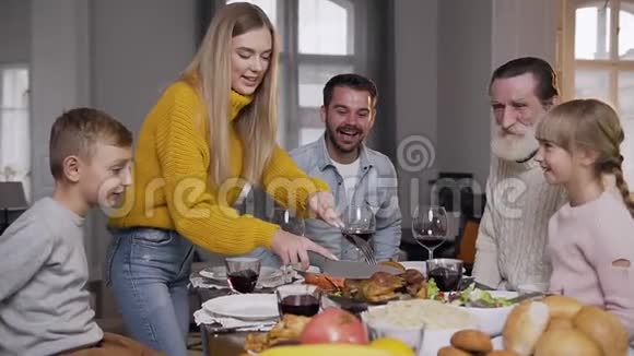 在家庭节日晚餐时穿着针织毛衣雕刻烤火鸡的微笑的女人视频的预览图