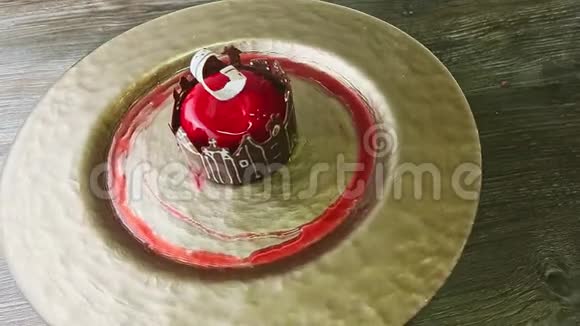 在金色盘子上旋转的城堡形状巧克力的红色釉面甜点中放大视频的预览图