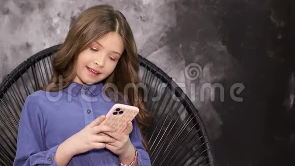 一个穿蓝色衬衫的女孩看着智能手机小玩意的照相机的肖像视频的预览图