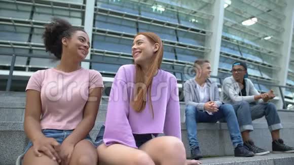 十几岁的男孩和女孩笑着分别坐在学校体育场尴尬的年龄视频的预览图