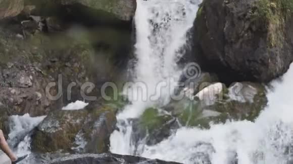 一位背着背包的女游客爬上悬崖举起双手站在一个大瀑布前视频的预览图