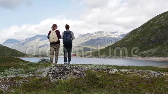两个女背包客站在一个山湖前欣赏风景视频的预览图