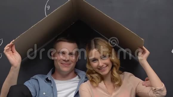 丈夫和妻子坐在纸板屋顶下梦想着家在一起视频的预览图