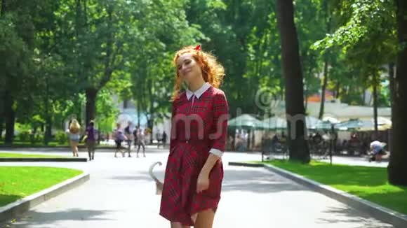 自信的红发女孩带着雨伞在公园里散步视频的预览图