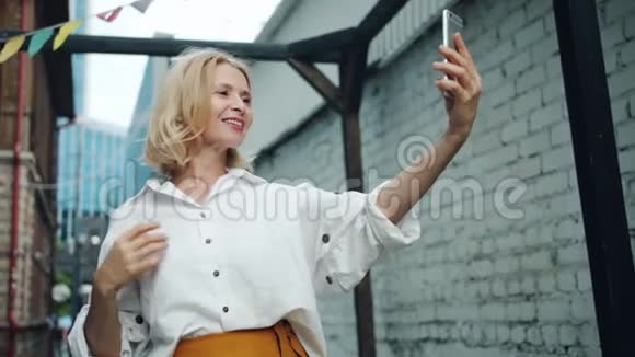 漂亮中年妇女在户外用智能手机自拍的慢动作视频的预览图