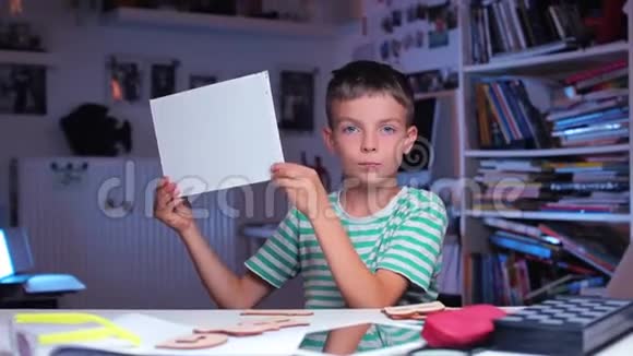 男孩捂着脸用一张白纸打开他的脸视频的预览图
