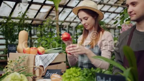 友好的女售货员在温室农场销售期间包装有机蔬菜视频的预览图