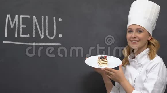 友好的女厨师把蛋糕放在盘子里菜单写在黑板上霍雷卡视频的预览图