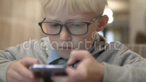 那个戴眼镜的男孩仔细地看着手机屏幕视频的预览图