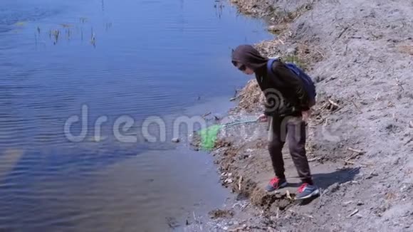 男孩正在用蝴蝶网在河上放青蛙和鱼视频的预览图