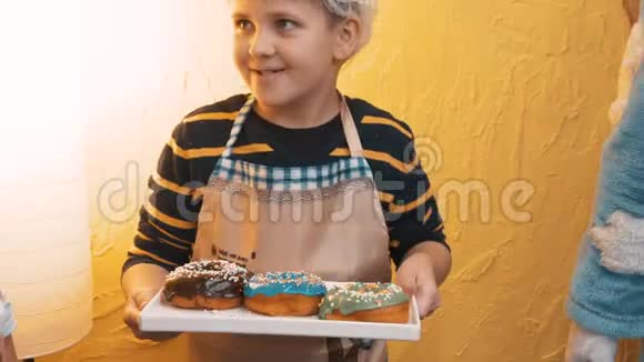 可爱的快乐小男孩拿着托盘和美味的甜面圈视频的预览图