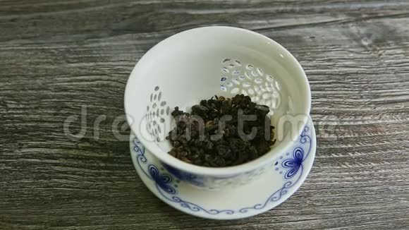 在白瓷茶壶里用干茶叶灌上热水视频的预览图
