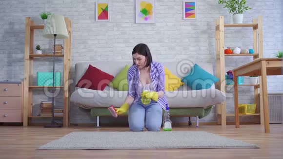 戴手套的年轻女子很乐意用手清洁地毯视频的预览图