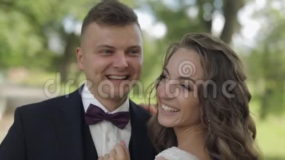白人新郎和新娘在公园里笑新婚夫妇新婚快乐视频的预览图