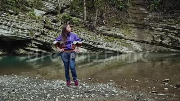 美丽的女孩站在那里双手放在干净的河岸上的臀部视频的预览图