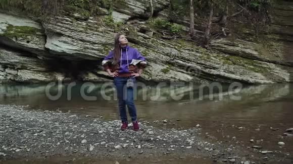 快乐的女孩站着双手放在湖边的臀部上她抬起头来视频的预览图