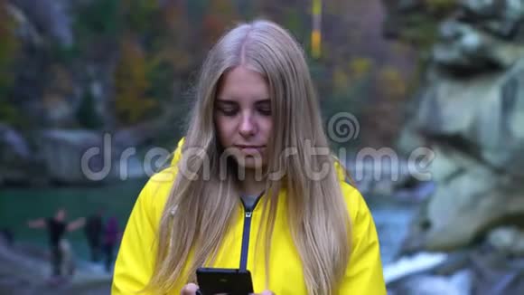 年轻有魅力的学生自由职业者女朋友女艺术家在秋天的山上使用她的智能手机视频的预览图