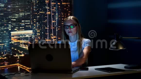戴眼镜的聪明女人在智能手机上阅读信息同时在电脑上工作视频的预览图
