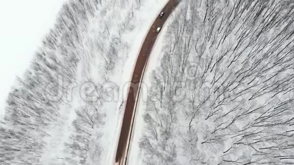 路面顶部向下汽车通过一个滑雪覆盖的交叉口在结冰的路面上驾驶的汽车上方飞行视频的预览图