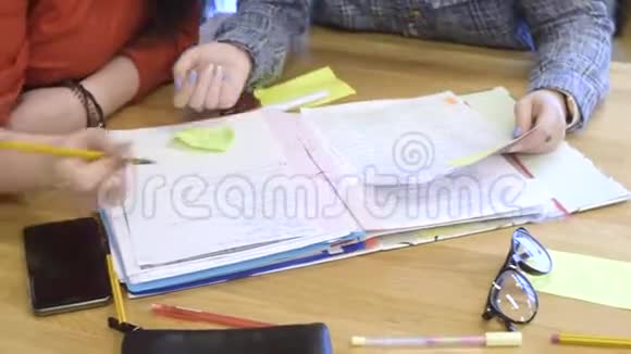 女孩教她的朋友做家庭作业看合同家庭培训贴纸笔记笔记本眼镜学生视频的预览图