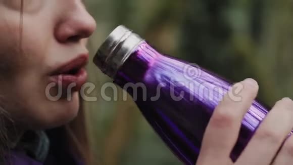 可爱的女孩正在特写镜头中从热水瓶里喝背景上有苔藓覆盖的童话森林视频的预览图
