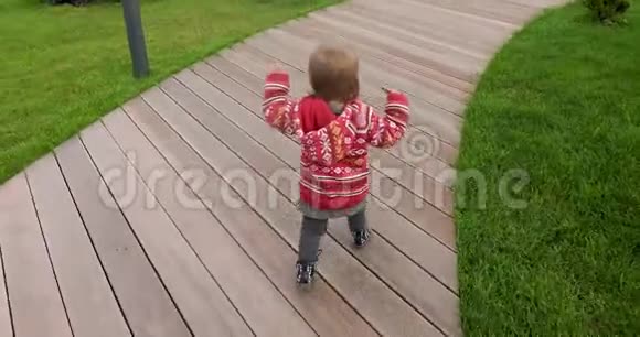 穿着红色毛衣的活跃孩子走在木路上视频的预览图