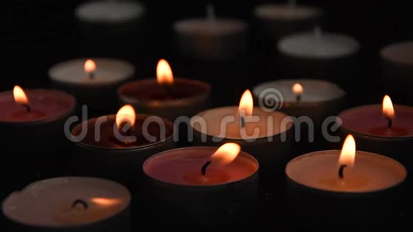 在黑色背景上组合在一起的点燃的茶光蜡烛的特写视频的预览图