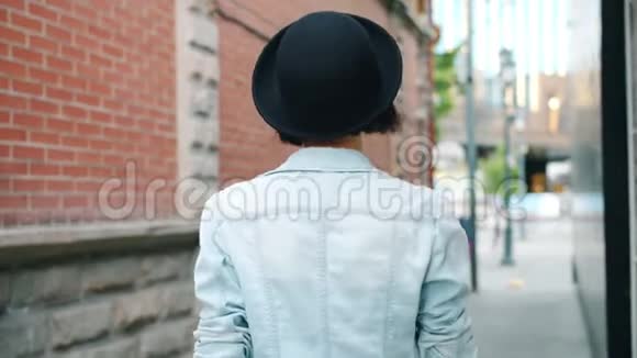 年轻女士走在户外的慢动作然后眨眼触摸帽子视频的预览图