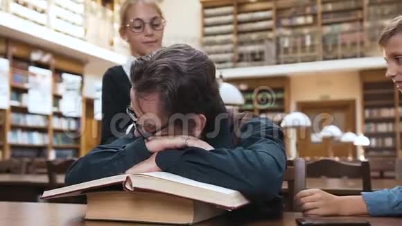 十几岁的小学生醒来时他们疲惫的尊敬的祖父睡在书上视频的预览图
