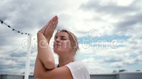 年轻的瑜伽女子用双手缓慢地在纳马斯特泥冥想视频的预览图