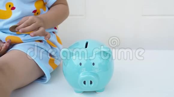 一个孩子正在把硬币放在蓝色的储蓄罐里为未来的概念储蓄儿童教育视频的预览图