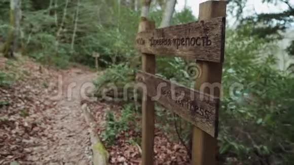 一个运动女孩沿着一条小路走过森林中的一个木制路标视频的预览图