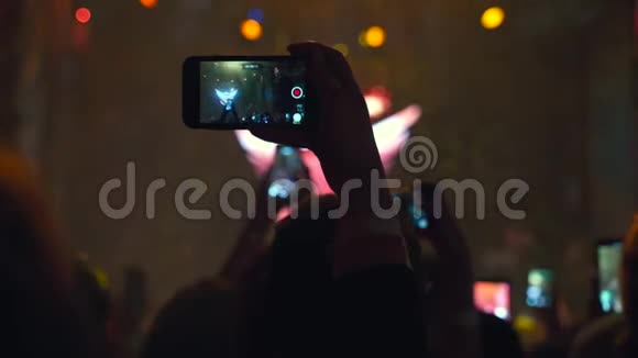 在拥挤的夜总会女人在她的手机上拍摄视频和照片光线在背景中移动慢慢视频的预览图