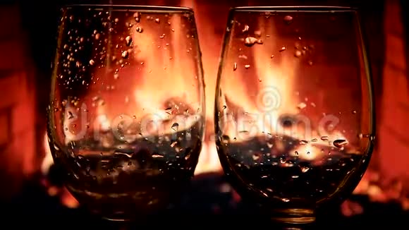 在壁炉背景下将白葡萄酒从瓶中倒入杯中缓慢移动视频的预览图