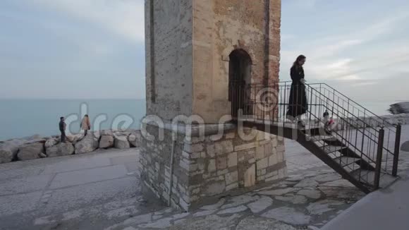 穿着黑衣的女人从海边的钟楼里走出来视频的预览图