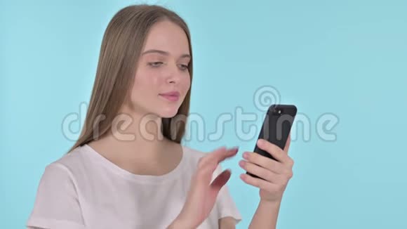 幸福的年轻女性在智能手机蓝色背景下庆祝成功视频的预览图
